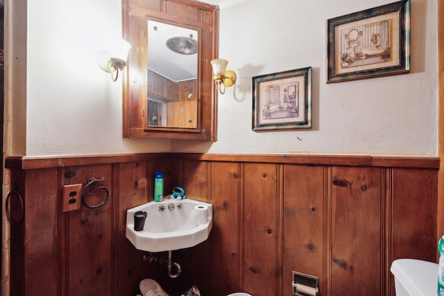 bathroom featuring wooden walls, toilet, and sink