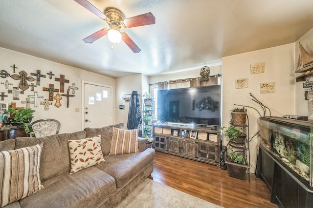 living room with ceiling fan, a glass covered fireplace, and wood finished floors