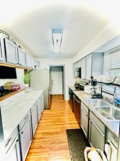 kitchen with gray cabinetry, appliances with stainless steel finishes, sink, and light hardwood / wood-style flooring