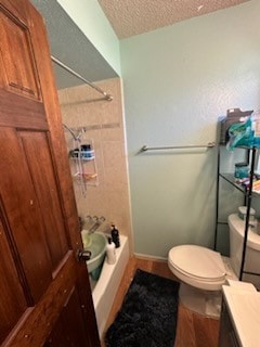 full bathroom with a textured ceiling, vanity, toilet, and shower / washtub combination