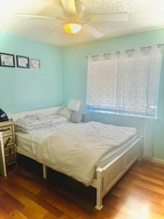 bedroom with ceiling fan, hardwood / wood-style flooring, and a textured ceiling