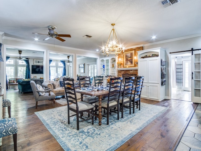 dining room with a barn door, ceiling fan with notable chandelier, dark hardwood / wood-style flooring, a textured ceiling, and ornamental molding