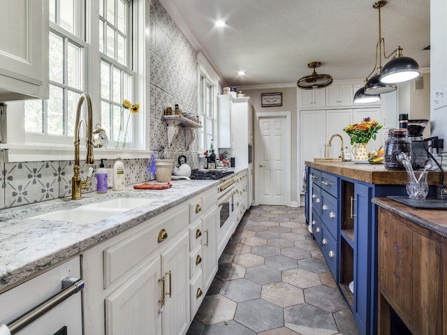 kitchen featuring hanging light fixtures, tasteful backsplash, white cabinets, butcher block counters, and blue cabinetry