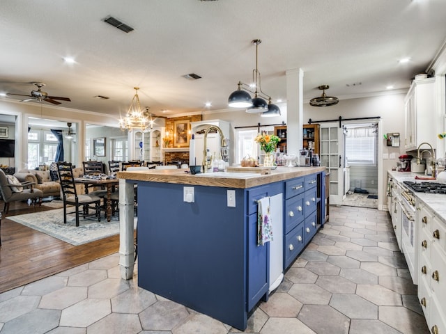 kitchen with blue cabinets, decorative light fixtures, white cabinetry, a barn door, and light hardwood / wood-style floors