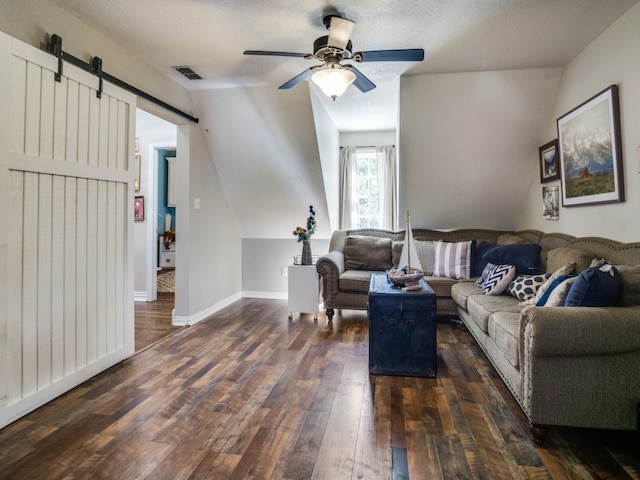 living room featuring lofted ceiling, ceiling fan, dark wood-type flooring, and a barn door