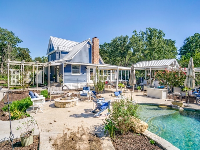 rear view of property with a patio and an outdoor fire pit