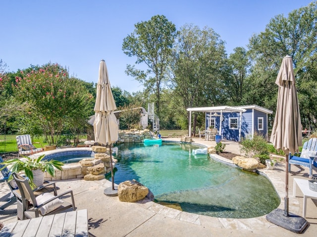 view of swimming pool featuring an in ground hot tub and an outbuilding