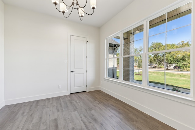 spare room featuring light wood-type flooring and a chandelier