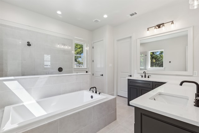 bathroom with plus walk in shower, a wealth of natural light, tile patterned flooring, and vanity