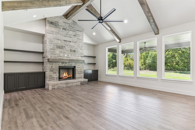 unfurnished living room featuring light hardwood / wood-style floors, beamed ceiling, and a fireplace