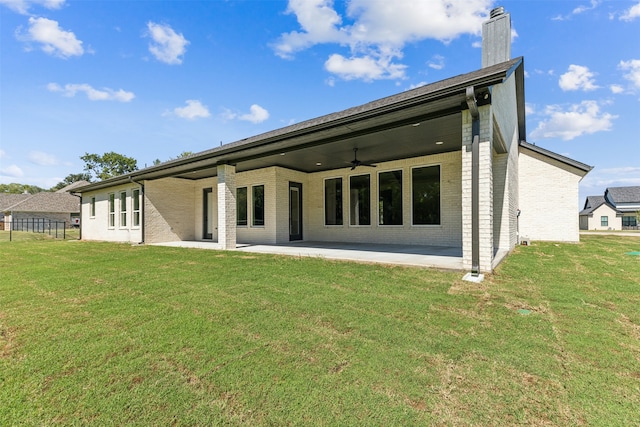 rear view of house featuring ceiling fan, a lawn, and a patio area