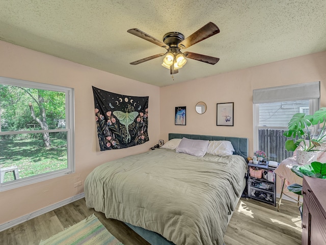 bedroom with light hardwood / wood-style flooring, ceiling fan, and a textured ceiling