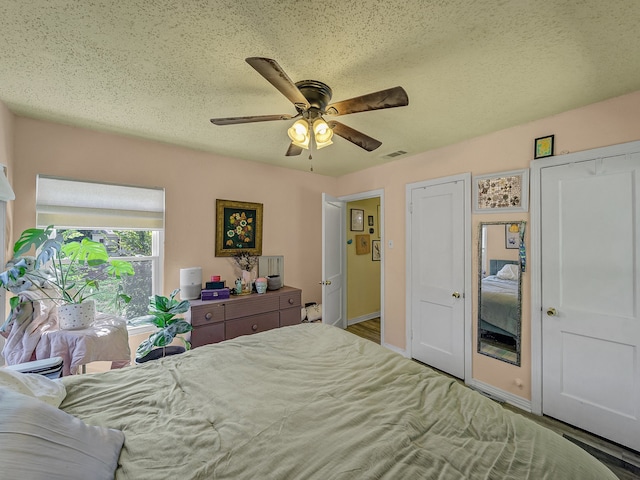 bedroom featuring ceiling fan, hardwood / wood-style floors, and a textured ceiling