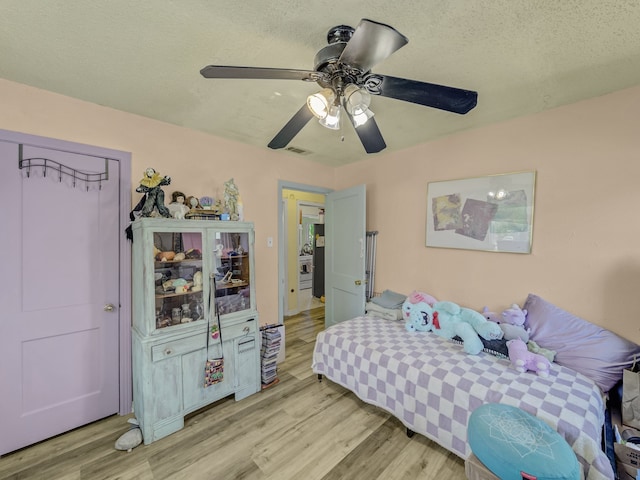 bedroom featuring ceiling fan, a textured ceiling, and light hardwood / wood-style floors