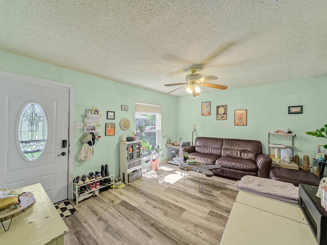 living room featuring ceiling fan, a textured ceiling, and light hardwood / wood-style floors