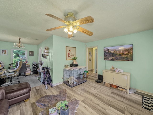 living room featuring a textured ceiling, ceiling fan with notable chandelier, and light hardwood / wood-style floors