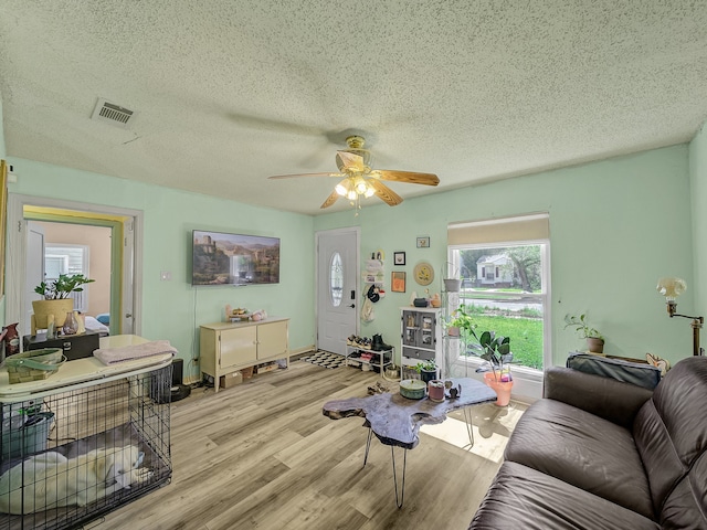 living room featuring light wood-type flooring, ceiling fan, and a healthy amount of sunlight