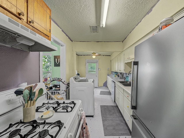 kitchen featuring ceiling fan, white cabinets, stainless steel dishwasher, white range with gas stovetop, and washing machine and dryer