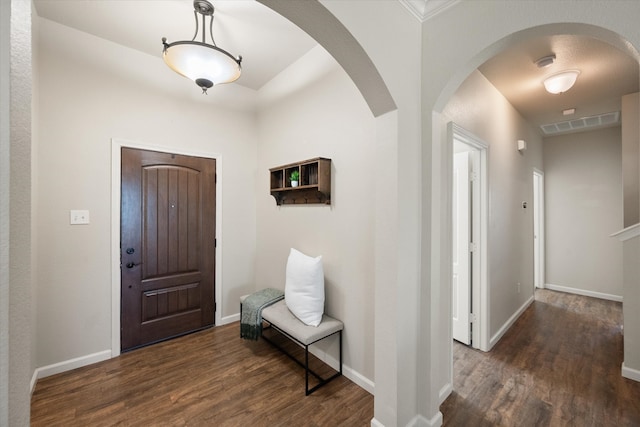 foyer entrance featuring visible vents, baseboards, arched walkways, and dark wood-type flooring