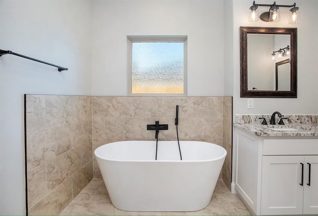 bathroom featuring tile walls, vanity, a washtub, and tile patterned floors