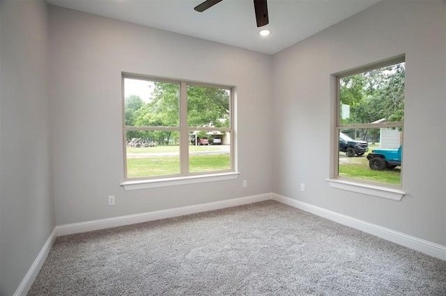 carpeted spare room with ceiling fan and plenty of natural light