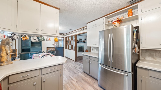 kitchen featuring open shelves, light wood-style flooring, gray cabinets, freestanding refrigerator, and a textured ceiling