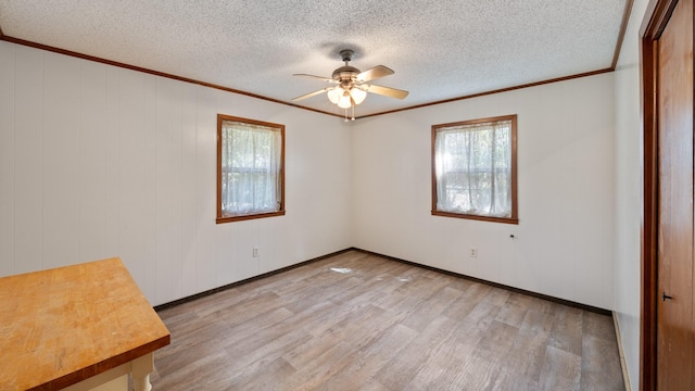 spare room featuring ceiling fan, a textured ceiling, light wood-style flooring, and ornamental molding