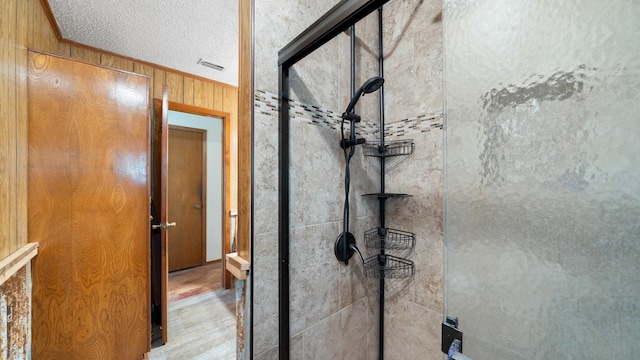 bathroom featuring visible vents, wood finished floors, wooden walls, a shower stall, and crown molding