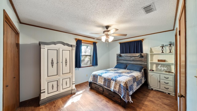 bedroom with ceiling fan, hardwood / wood-style floors, a textured ceiling, a closet, and ornamental molding