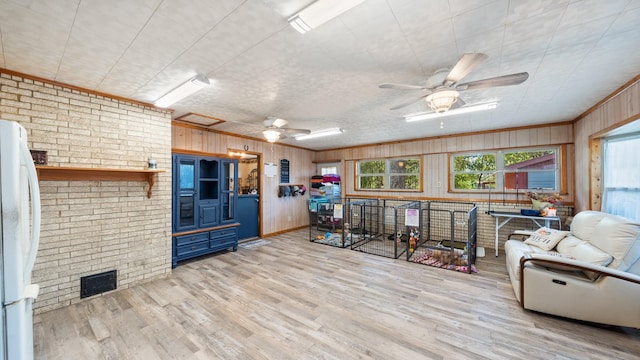 interior space with visible vents, wood finished floors, freestanding refrigerator, brick wall, and ceiling fan