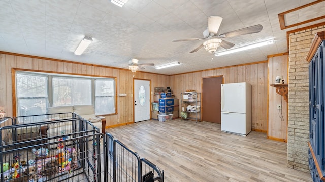 miscellaneous room featuring wood finished floors, baseboards, ceiling fan, ornamental molding, and wood walls