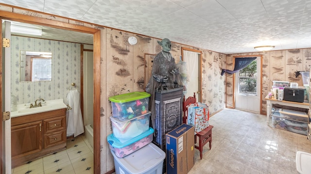 interior space featuring wallpapered walls, light floors, and a sink