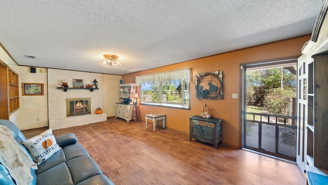 living room with visible vents, plenty of natural light, a fireplace, and wood finished floors