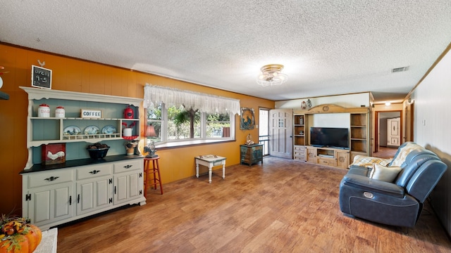 living area with visible vents, a textured ceiling, and light wood-type flooring