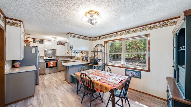 dining area featuring light wood-type flooring and a textured ceiling