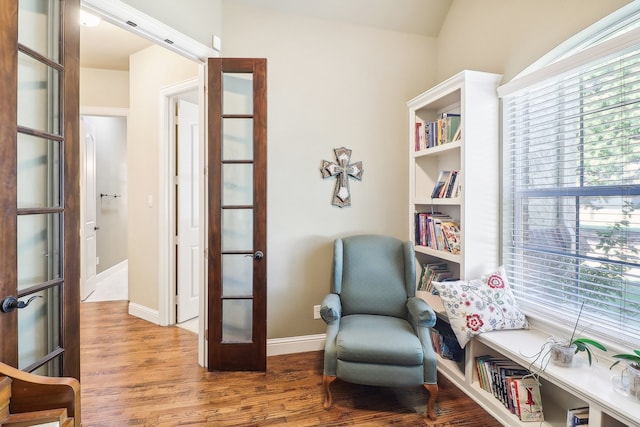 living area with french doors, hardwood / wood-style flooring, and lofted ceiling