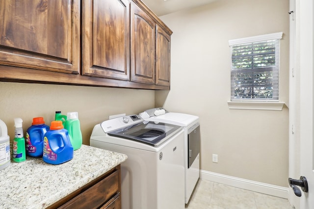 laundry area featuring separate washer and dryer, light tile patterned flooring, and cabinets