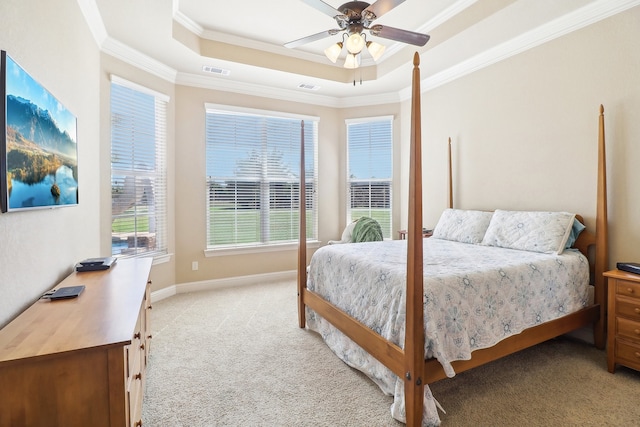 carpeted bedroom with a tray ceiling, ornamental molding, and ceiling fan