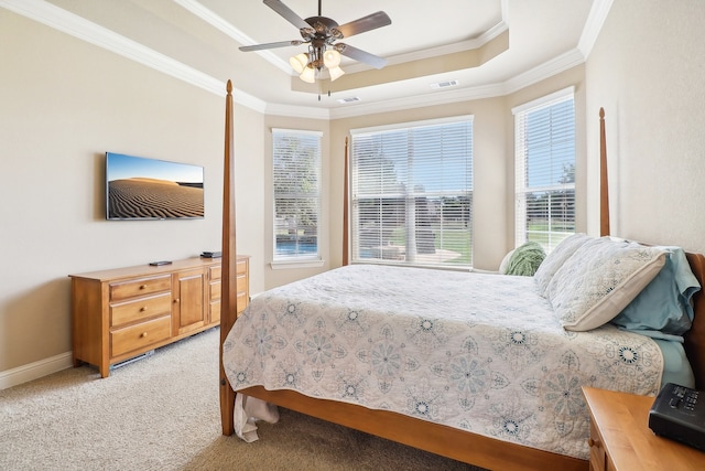 carpeted bedroom with a tray ceiling, ceiling fan, and crown molding