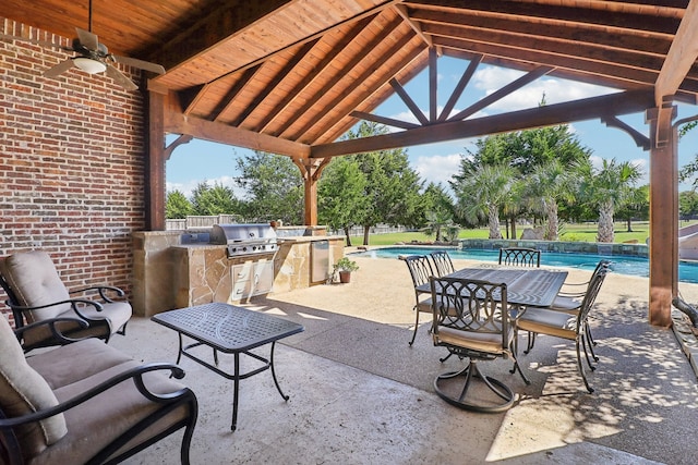 view of patio featuring exterior kitchen, ceiling fan, and a grill