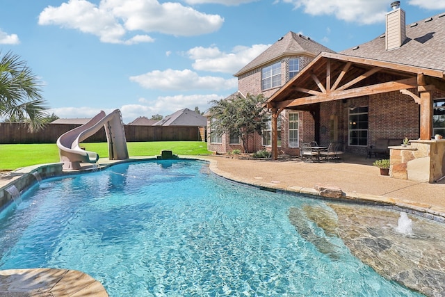 view of swimming pool featuring pool water feature, a patio, a water slide, and a yard