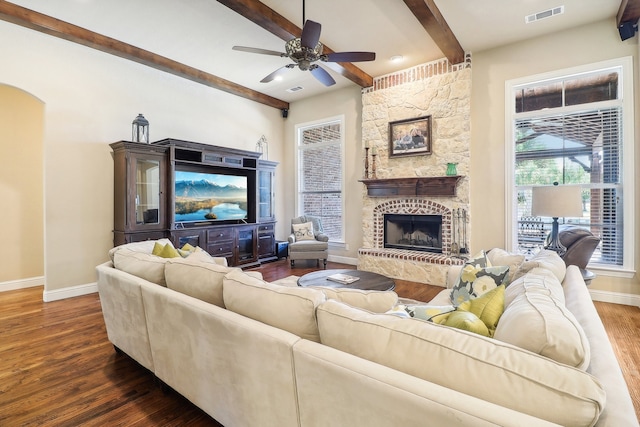 living room featuring a stone fireplace, beam ceiling, dark hardwood / wood-style floors, and ceiling fan