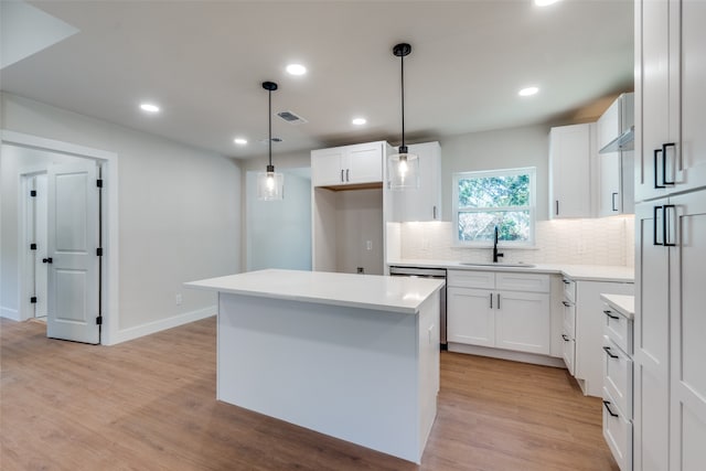 kitchen with light wood-type flooring, sink, pendant lighting, white cabinets, and a center island