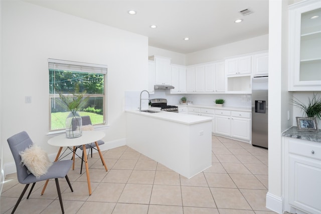 kitchen with kitchen peninsula, appliances with stainless steel finishes, sink, light tile patterned floors, and white cabinets