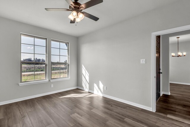 spare room with ceiling fan with notable chandelier and dark hardwood / wood-style flooring