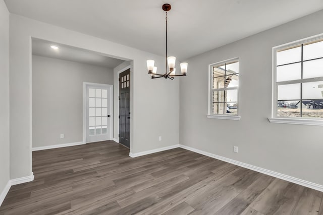 unfurnished room featuring a notable chandelier and dark hardwood / wood-style floors