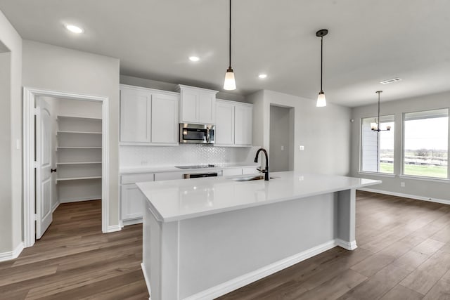 kitchen featuring white cabinetry, sink, an island with sink, and pendant lighting