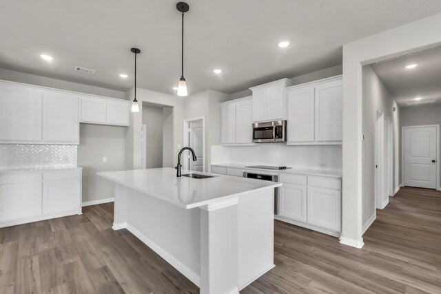 kitchen with white cabinets, hardwood / wood-style floors, an island with sink, and sink