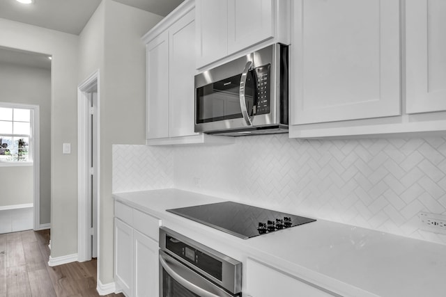 kitchen with backsplash, white cabinets, stainless steel appliances, and dark hardwood / wood-style floors