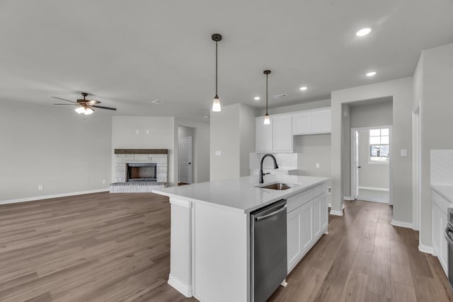 kitchen featuring white cabinets, sink, decorative light fixtures, a center island with sink, and dishwasher